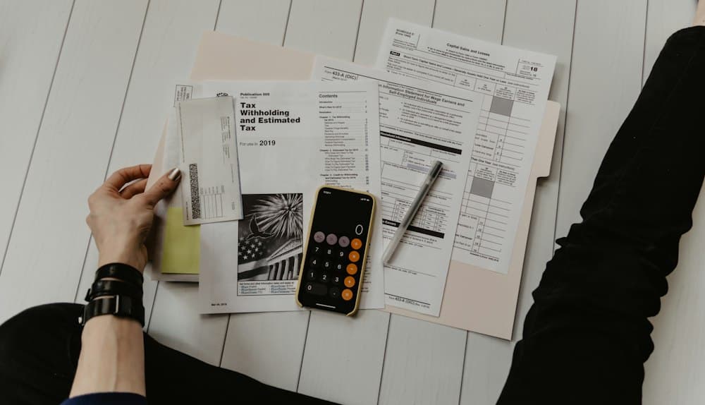 Mesa de escritório com notas fiscais, calculadora e computador para emissão de NF-e na SEFAZ